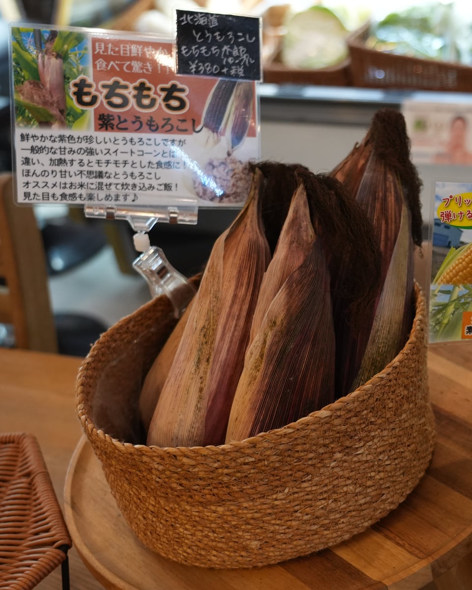 皮とひげがついたままの、かごに立てた紫とうもろこし